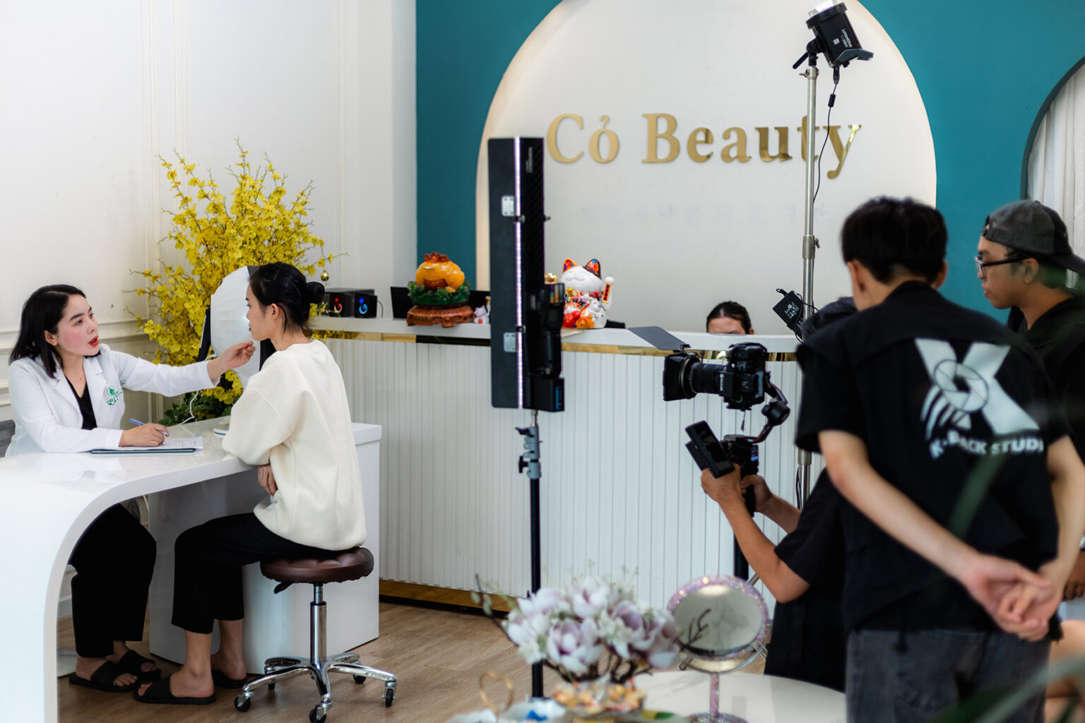 Cameraman theo giờ K-BLACK quay hậu trường buổi tư vấn tại spa Cỏ Beauty, bác sĩ áo blouse trắng trò chuyện với khách nữ