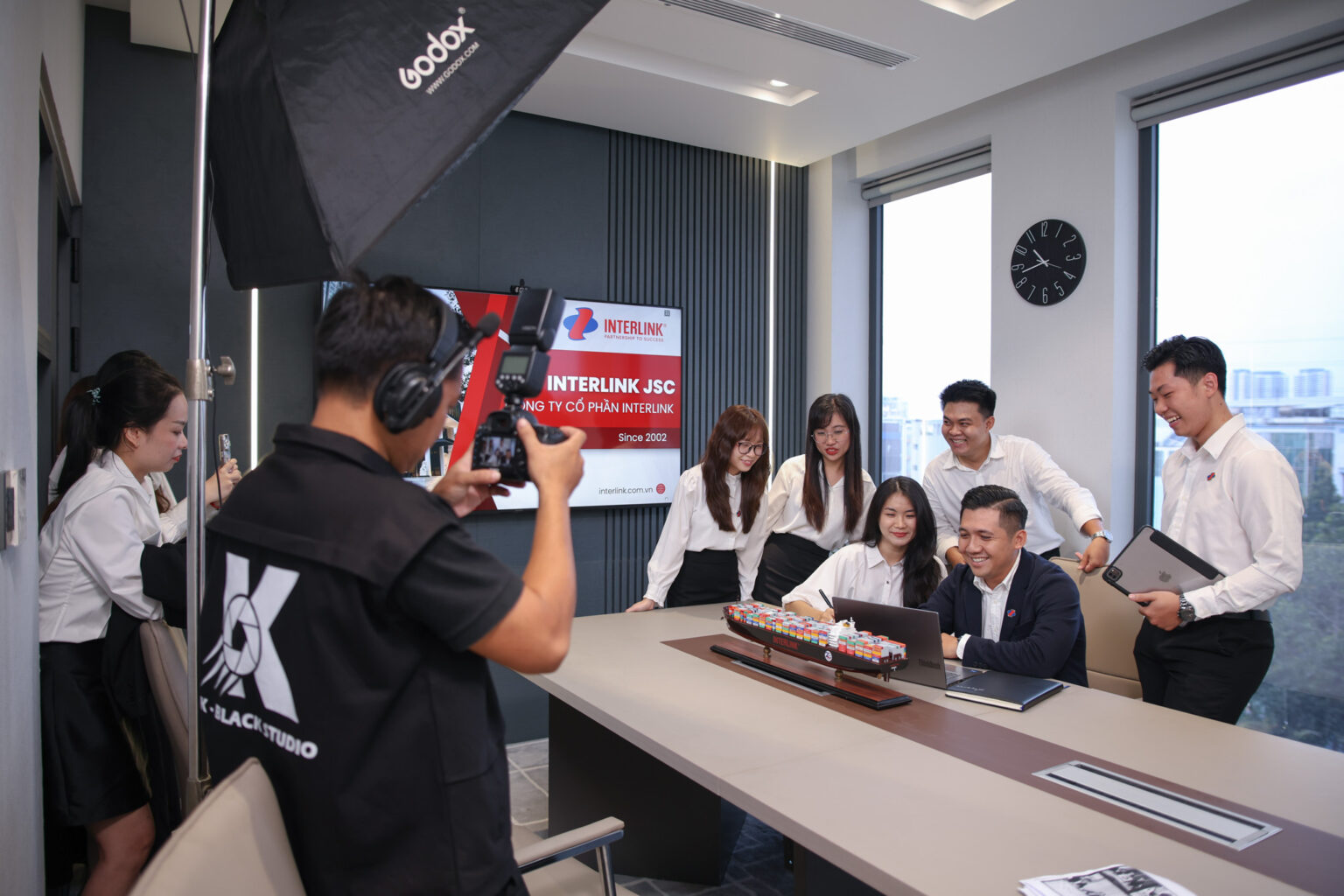 Hậu trường sản xuất hình ảnh doanh nghiệp: ê-kíp K-BLACK ghi hình đội ngũ khách hàng quanh bàn họp với đèn softbox