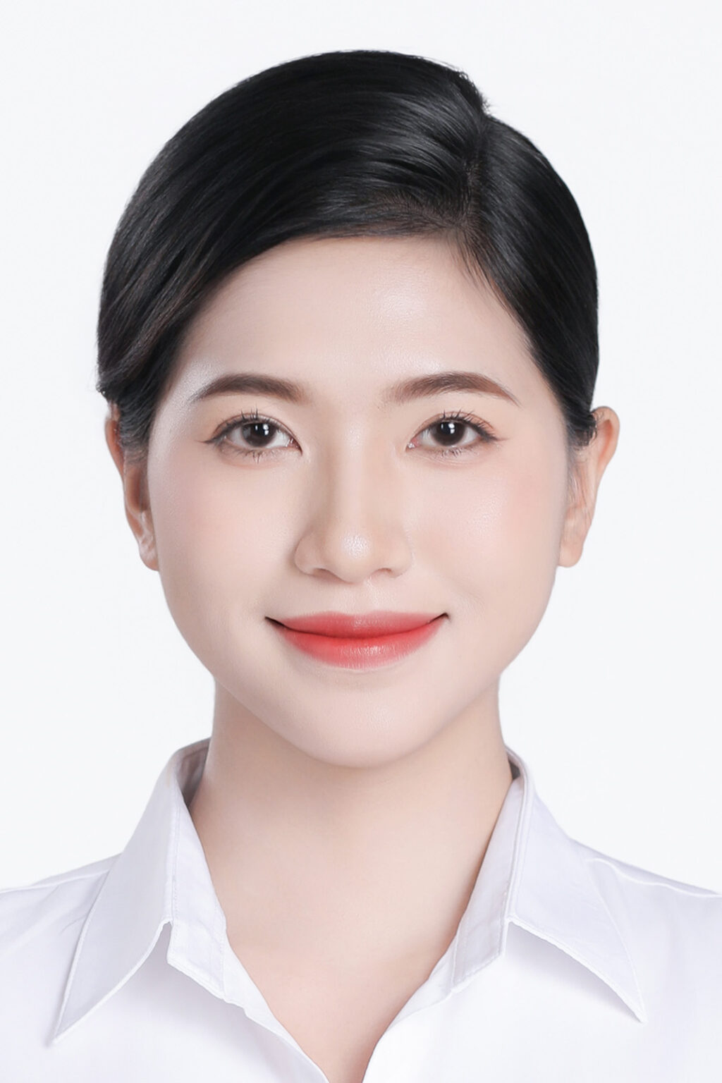 Ảnh thẻ nữ nền trắng, sơ mi trắng cổ bẻ, tóc búi gọn lộ trán và tai, mỉm cười nhẹ